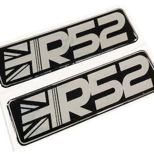 May include: Two black and silver car badges featuring the text "R52" and a Union Jack design.