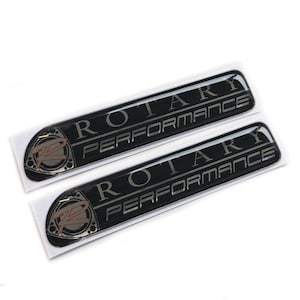 May include: Two black and silver "Rotary Performance" emblems with a red and silver rotary engine logo.