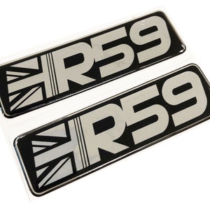 Op de afbeelding: Twee zwarte en zilveren auto-emblemen met de tekst "R59" en een Union Jack-ontwerp.