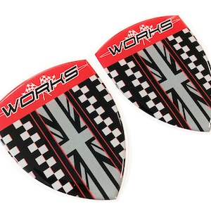 May include: Two red, black, and white car emblems with the word "WORKS" in white lettering. The emblems feature a checkered pattern and a Union Jack flag design.