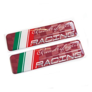 Puede incluir: Dos emblemas de coche rojo, blanco y verde con las palabras "Quadrifoglio Racing" en letras plateadas.