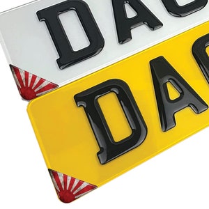 Può includere: Due targhe gialle e bianche con la parola "DAB" in lettere 3D nere. Le targhe hanno un design di sole nascente giapponese rosso e bianco sugli angoli inferiori.