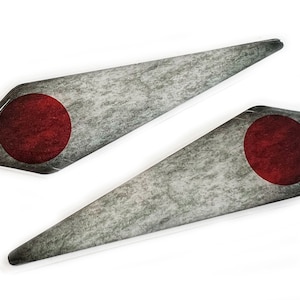 May include: Two gray and white diamond-shaped stickers with a red circle in the center. The stickers have a distressed, textured look.