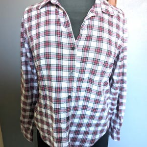May include: A white, red, and black plaid long-sleeve button-up shirt.