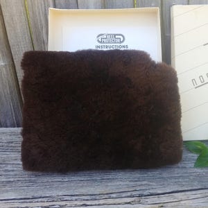 May include: A brown faux fur heel protector in its original packaging. The box has the words "Heel Protector" and "Instructions" printed on it.
