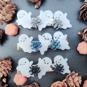 May include: Set of four white ghost hair clips with black and blue glitter spider embellishments.