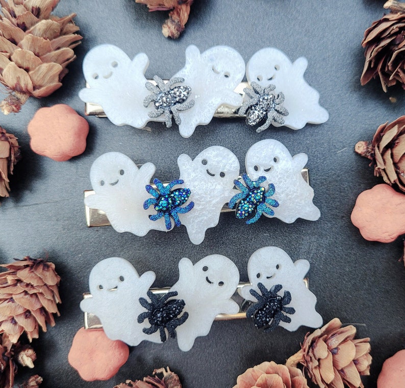 May include: Set of four white ghost hair clips with black and blue glitter spider embellishments.