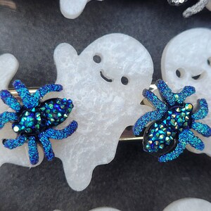 May include: Two blue iridescent glitter spider hair clips with white ghost-shaped hair clips.