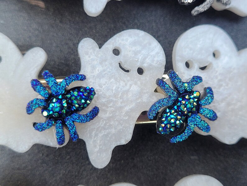 May include: Two blue iridescent glitter spider hair clips with white ghost-shaped hair clips.