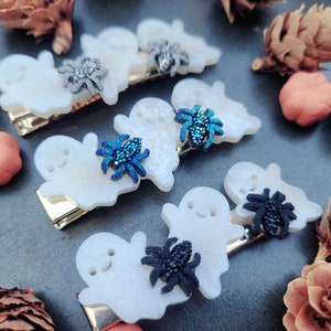 May include: Set of six white ghost hair clips with sparkly blue and black spiders. The clips are perfect for Halloween.