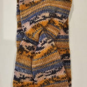 以下が含まれることがあります： ねじれたデザインのニットヘッドバンド。ヘッドバンドはオレンジ、ブラウン、ブルー、ピンクのストライプです。