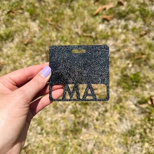 May include: Black glitter name tag with the letters "MA" cut out.