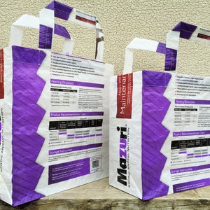 May include: Two white and purple tote bags with handles. The bags feature the text "Mazuri Exotic Animal Nutrition" and "Alpaca and Maintainer". The bags have product information printed on them.