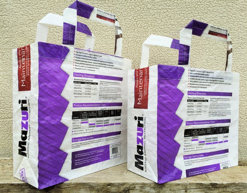 May include: Two white and purple tote bags with handles. The bags feature the text "Mazuri Exotic Animal Nutrition" and "Alpaca and Maintainer". The bags have product information printed on them.