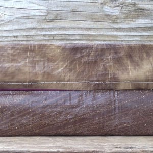 May include: A rectangular, handmade box with a two-tone design. The bottom half is a dark brown, textured material, while the top transitions from a lighter brown to a pale yellow. White stitching and a purple accent line the seam.