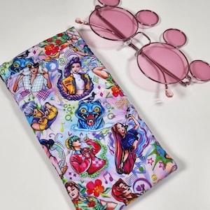 May include: A rectangular fabric glasses case featuring a vibrant, multi-colored graphic print of various anime-style characters, blue cat-like creatures, and musical notes, paired with a pair of round, pink-tinted glasses with thin metal frames.