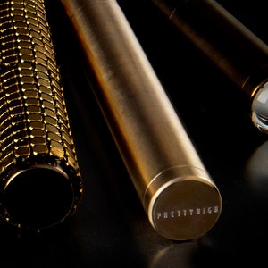 May include: Three gold-colored metal tubes. The tube in the center has the words "PRETTY HIGH" engraved on the end.