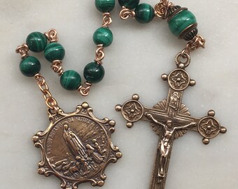 Könnte beinhalten: Ein Rosenkranz aus grünem Malachit mit einem bronzenen Kruzifix und einer bronzenen Medaille mit der Darstellung der Muttergottes von Fatima. Die Medaille trägt die Inschrift "Ave Maria, Rosa Mystica, Mater Dei, Ora Pro Nobis".