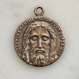 May include: A bronze pendant featuring a depiction of Jesus Christ's face and the inscription "ILLUMINA DOMINE VULTUM TUUM SUPER NOS".