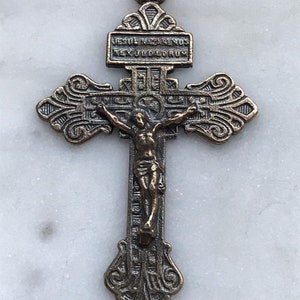 Puede incluir: Un crucifijo de bronce con un diseño detallado y una figura de Jesucristo en la cruz. La inscripción en la cruz dice "Jesus Nazarenos Rex Judæorum".