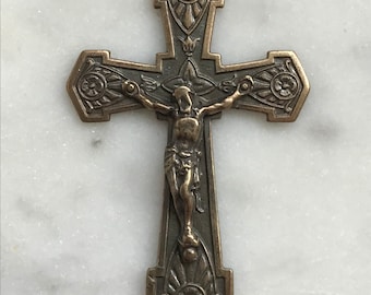 May include: A bronze crucifix pendant with an ornate design and a figure of Jesus Christ on the cross.