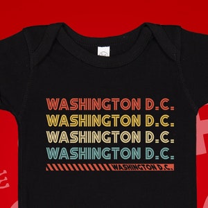 May include: Black baby onesie with a retro design featuring the text "WASHINGTON D.C." repeated four times in different colors.