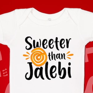 May include: White baby onesie with the text "Sweeter than Jalebi" in black font. A yellow and orange swirl graphic is above the text.