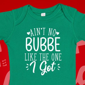 May include: A green baby onesie with white text that reads "Ain't no bubbe like the one I got".