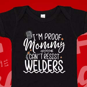 May include: Black baby onesie with white text that reads "I'm proof mommy can't resist welders". The text is surrounded by small hearts and stars.