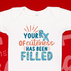 May include: White baby onesie with a blue and orange graphic that says "Your RX of cuteness has been filled".