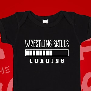May include: Black baby onesie with white text that reads "Wrestling Skills Loading" with a progress bar underneath.