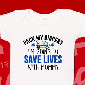 May include: White baby onesie with blue text that reads "Pack my diapers I'm going to save lives with mommy". A small ambulance graphic is above the text.