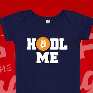 May include: A navy blue baby onesie with the text "HODL ME" in white letters and a yellow Bitcoin symbol.