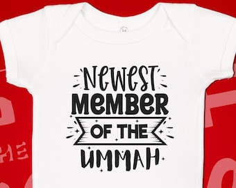 May include: White baby onesie with black text that reads "Newest Member of the Ummah".