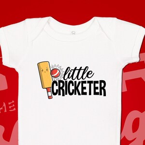 May include: White baby onesie with a cartoon cricket bat and ball. The text "little cricketer" is printed in black.