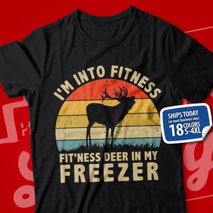 May include: Black t-shirt with a vintage-style sunset graphic and the text "I'm into fitness fit'ness deer in my freezer". A white sticker with the text "Ships today (or next business day) 18 colors S-4XL" is on the shirt.