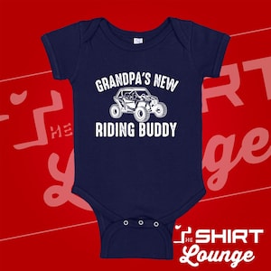Könnte beinhalten: Marineblaues Baby-Body mit weißem Text "GRANDPA'S NEW RIDING BUDDY" über einer Illustration eines Geländewagens. Der Body hat kurze Ärmel und drei Druckknöpfe am unteren Saum.