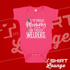 May include: Pink baby onesie with a white graphic that says "I'm proof mommy can't resist welders". The graphic includes a welding mask and a welding torch.