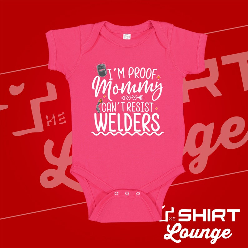 May include: Pink baby onesie with a white graphic that says "I'm proof mommy can't resist welders". The graphic includes a welding mask and a welding torch.