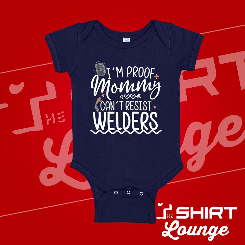 May include: A navy blue baby onesie with a white graphic that reads "I'm proof mommy can't resist welders". The graphic includes a welding mask, hearts, and an arrow.