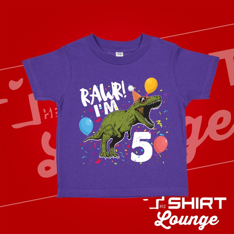 May include: Purple short-sleeved t-shirt with a green dinosaur wearing sunglasses and a party hat. The dinosaur is saying "Rawr! I'm 5" with confetti and balloons around it.