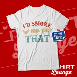 May include: White t-shirt with a vintage-style graphic that says "I'd Smoke That" with illustrations of a chicken, pig, and cow. The text "Ships Today (or next business day)" and "18 Colors S-4XL" are also on the shirt.