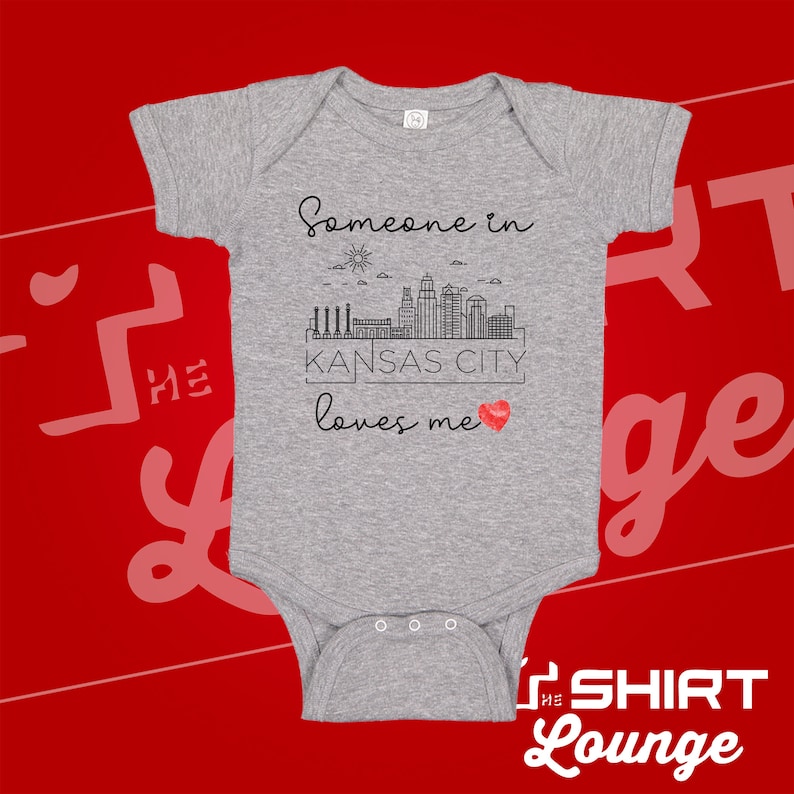 May include: Gray baby onesie with a black graphic of a city skyline and the text "Someone in Kansas City loves me" with a red heart.