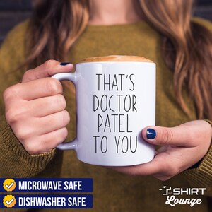 Pode incluir: Caneca de caf&eacute; de cer&acirc;mica branca com texto preto que diz "That's Doctor Patel To You". A caneca &eacute; adequada para microondas e lava-lou&ccedil;as.