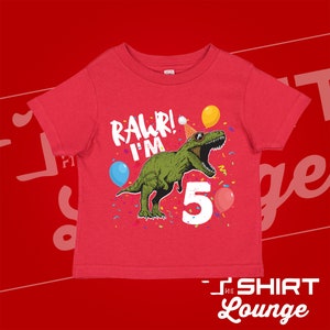 May include: Red short-sleeved t-shirt with a green dinosaur wearing a party hat and sunglasses. The dinosaur is saying "Rawr! I'm 5" with confetti and balloons around it.