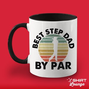 May include: White coffee mug with a black handle and black rim. The mug has a vintage-style graphic of a golfer with the text "Best Step Dad By Par".