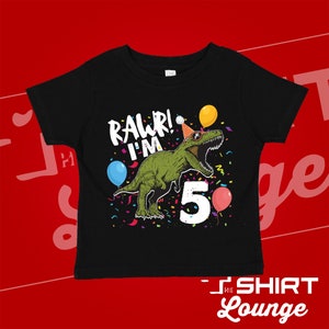 May include: Black t-shirt with a green dinosaur wearing a party hat and sunglasses. The dinosaur is surrounded by confetti and balloons. The text "Rawr! I'm 5" is printed on the shirt.