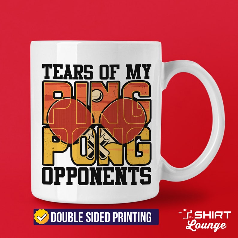 May include: White ceramic coffee mug with a vintage-style design featuring the text "Tears of my Ping Pong Opponents". The design includes two red and orange ping pong paddles with a white ball. The text is in black and the background is a faded orange and yellow.