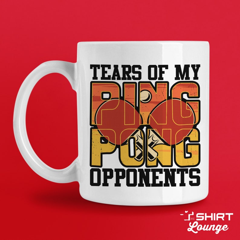 May include: White ceramic coffee mug with a graphic design of a ping pong paddle and ball. The text "Tears of my ping pong opponents" is printed on the mug.