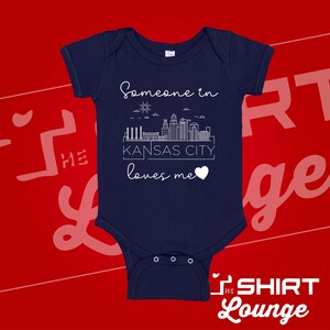 May include: Navy blue baby onesie with a white outline of the Kansas City skyline and the text "Someone in Kansas City loves me".